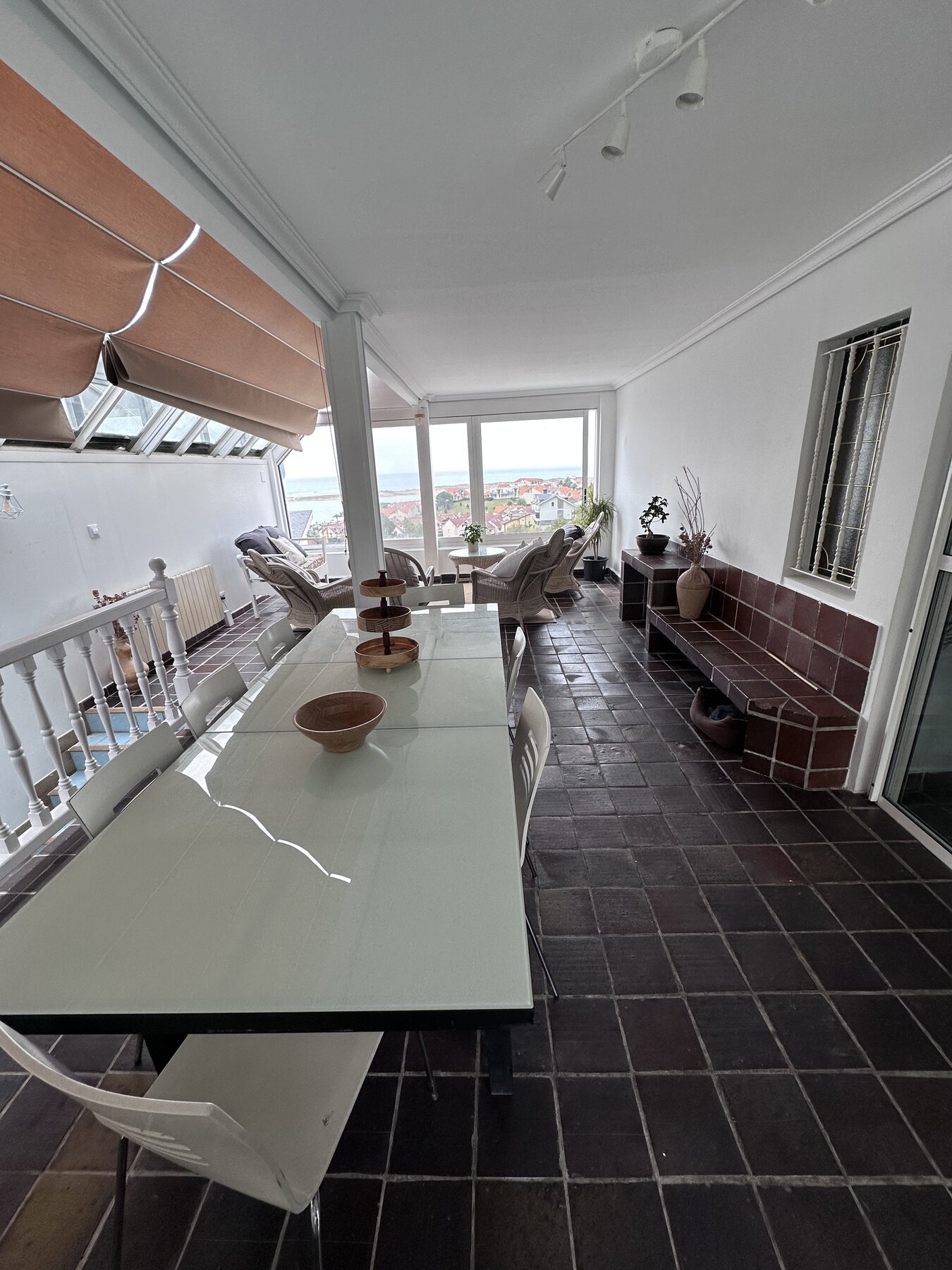 The covered terrace dining table at Casa Azul, with wicker seating and a view of the coast beyond.