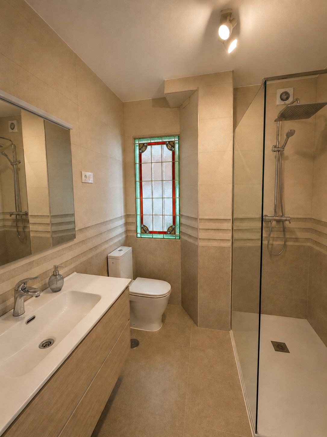 Un baño con una vidriera y una ducha de lluvia a ras de suelo.