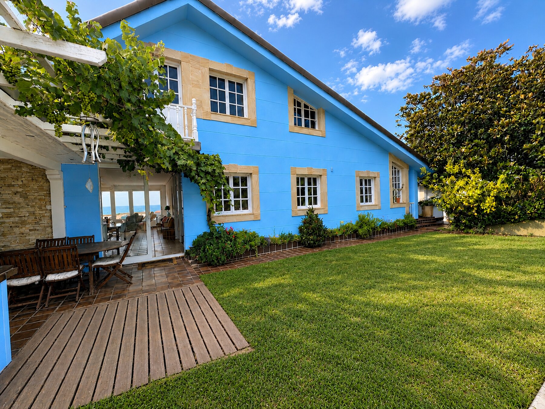 The blue exterior of Casa Azul, Cantabria, with a pergola and garden.
