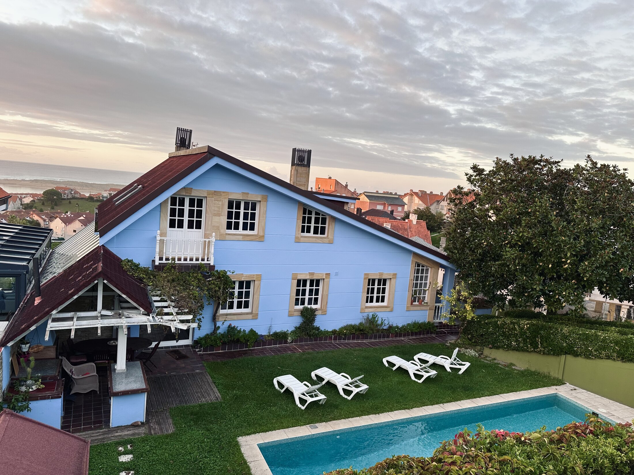 An aerial view of Casa Azul at sunset, with the pool and garden below and the sea in the distance.